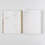 2026 Meadow Weekly Planner open to a week view, featuring floral design, gold spiral binding, and handwritten notes.