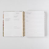 2026 Meadow Weekly Planner open to a week view, featuring floral design, gold spiral binding, and handwritten notes.