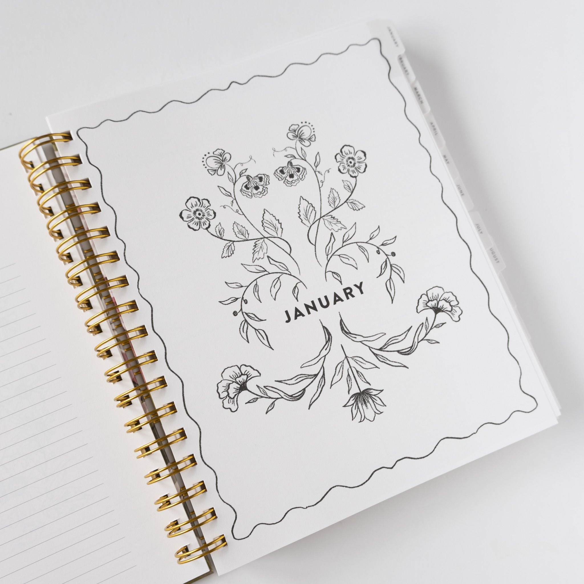 2026 Meadow Weekly Planner open to January page with floral illustrations and gold spiral binding.
