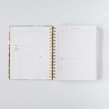 2026 planner bundle open to a weekly layout with gold spiral binding and floral cover design.