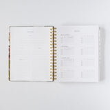 2026 planner bundle open to monthly overview and habit tracker pages with gold spiral binding.