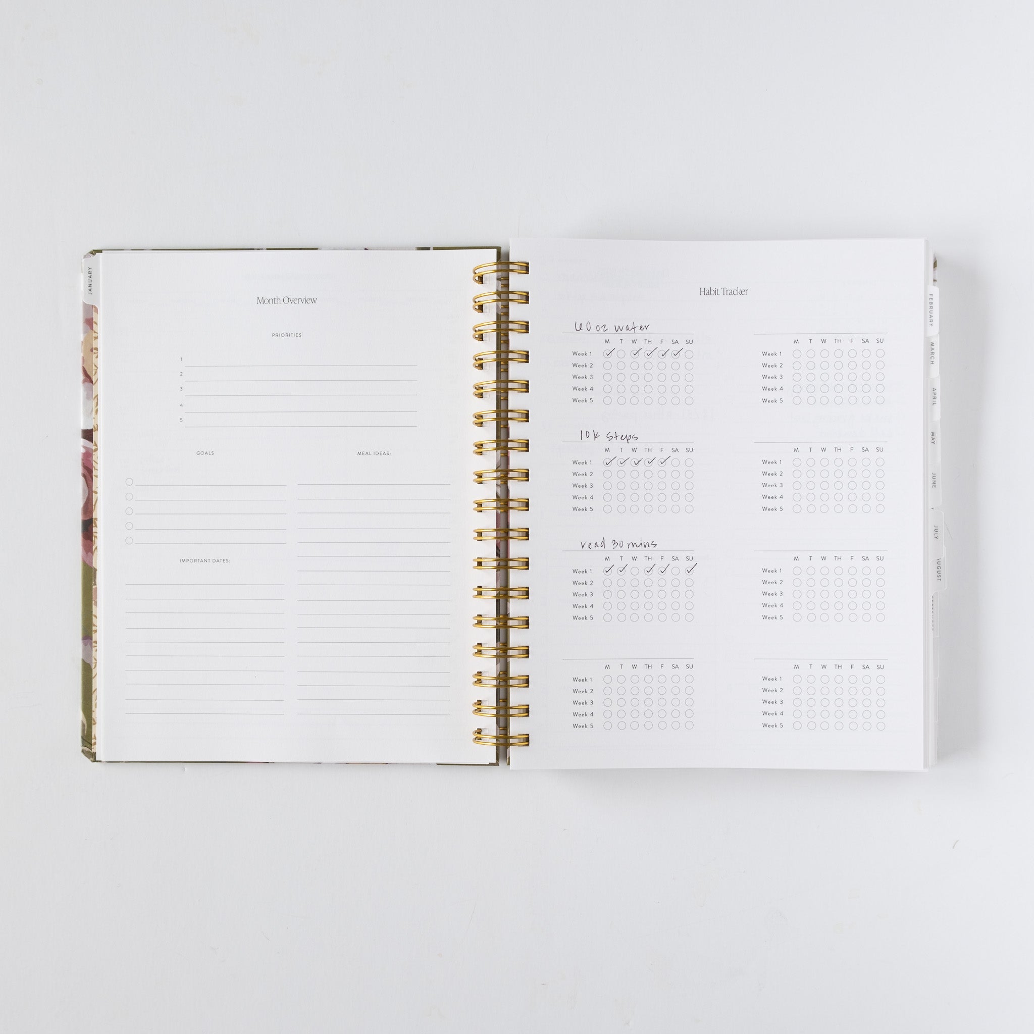 2026 planner bundle open to monthly overview and habit tracker pages with gold spiral binding.