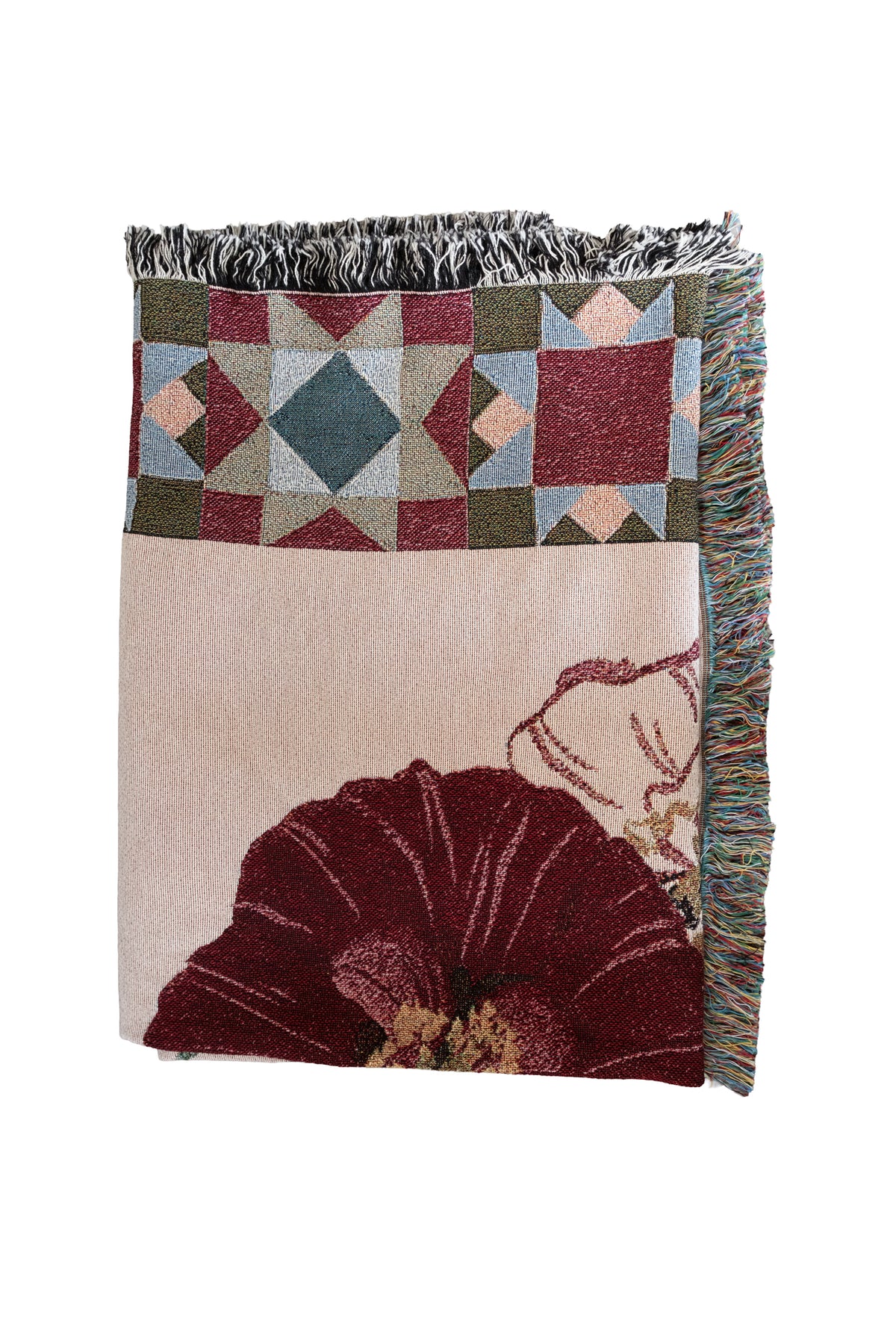 Folded woven fabric blanket with a red floral design, geometric star patterns, and fringed edges.