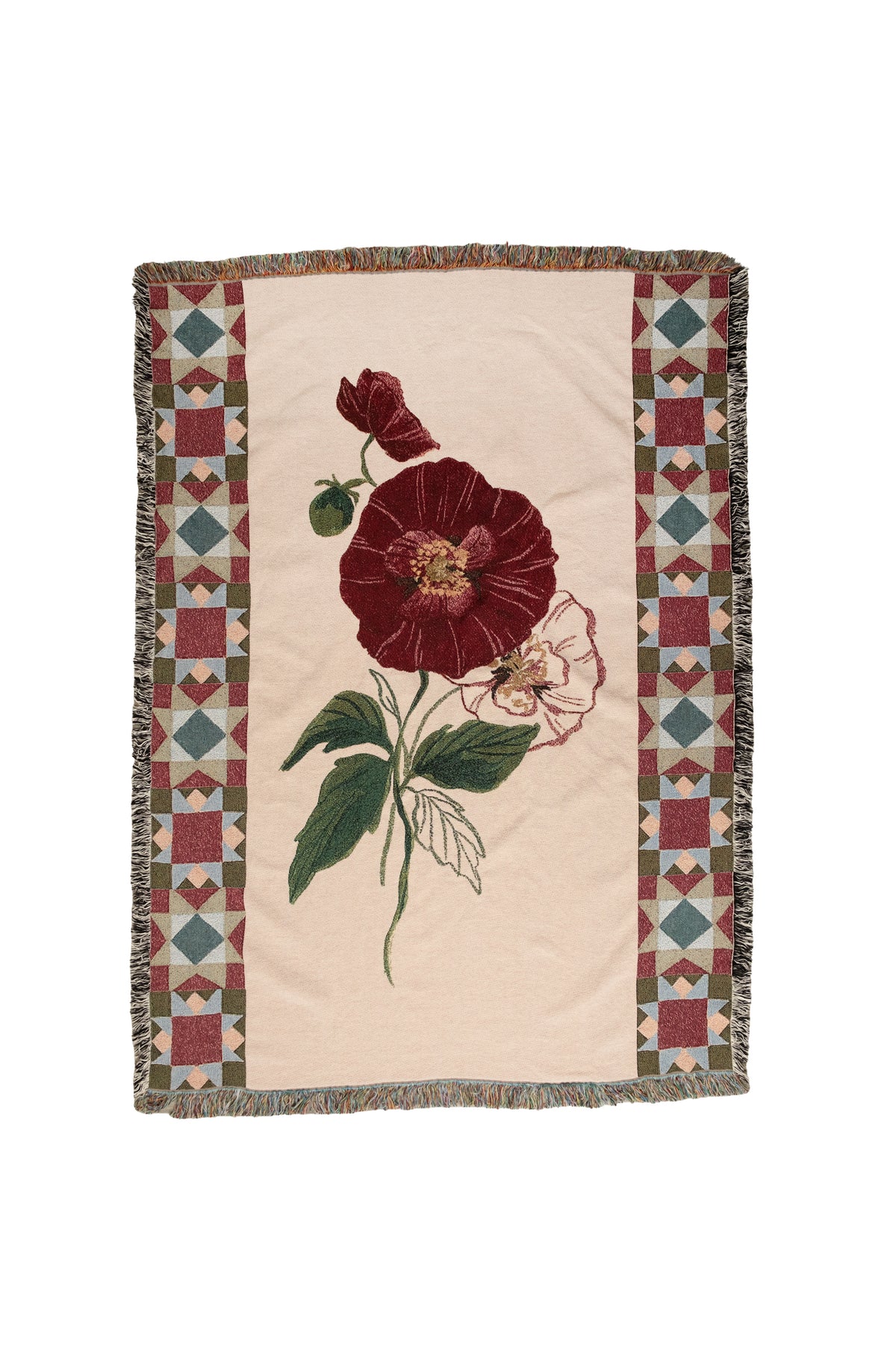 Cream woven blanket with a large red flower, green leaves, and geometric patterned borders with fringed edges.