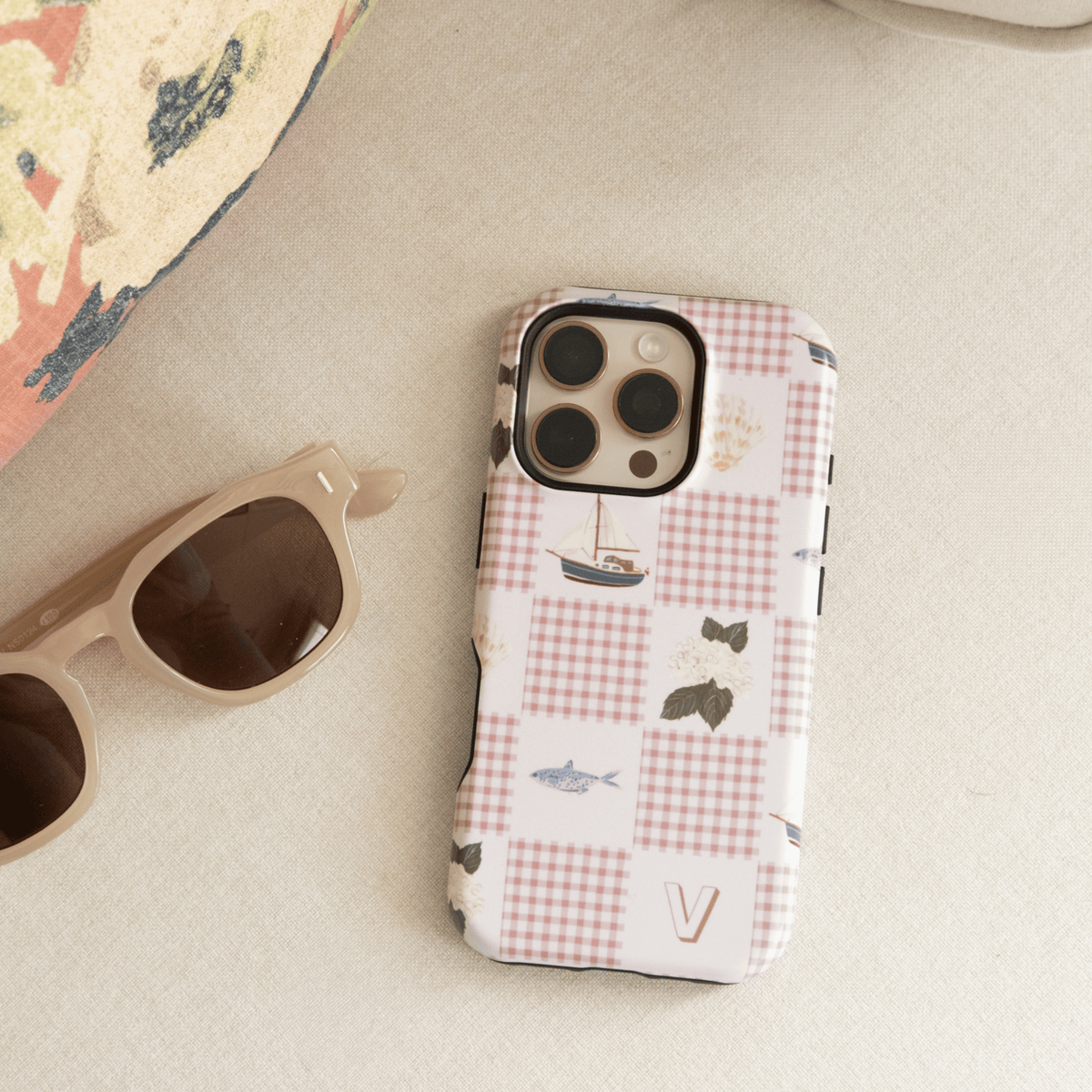 Coastal Personalized iPhone case with the initial V, lying on a beach towel beside sunglasses