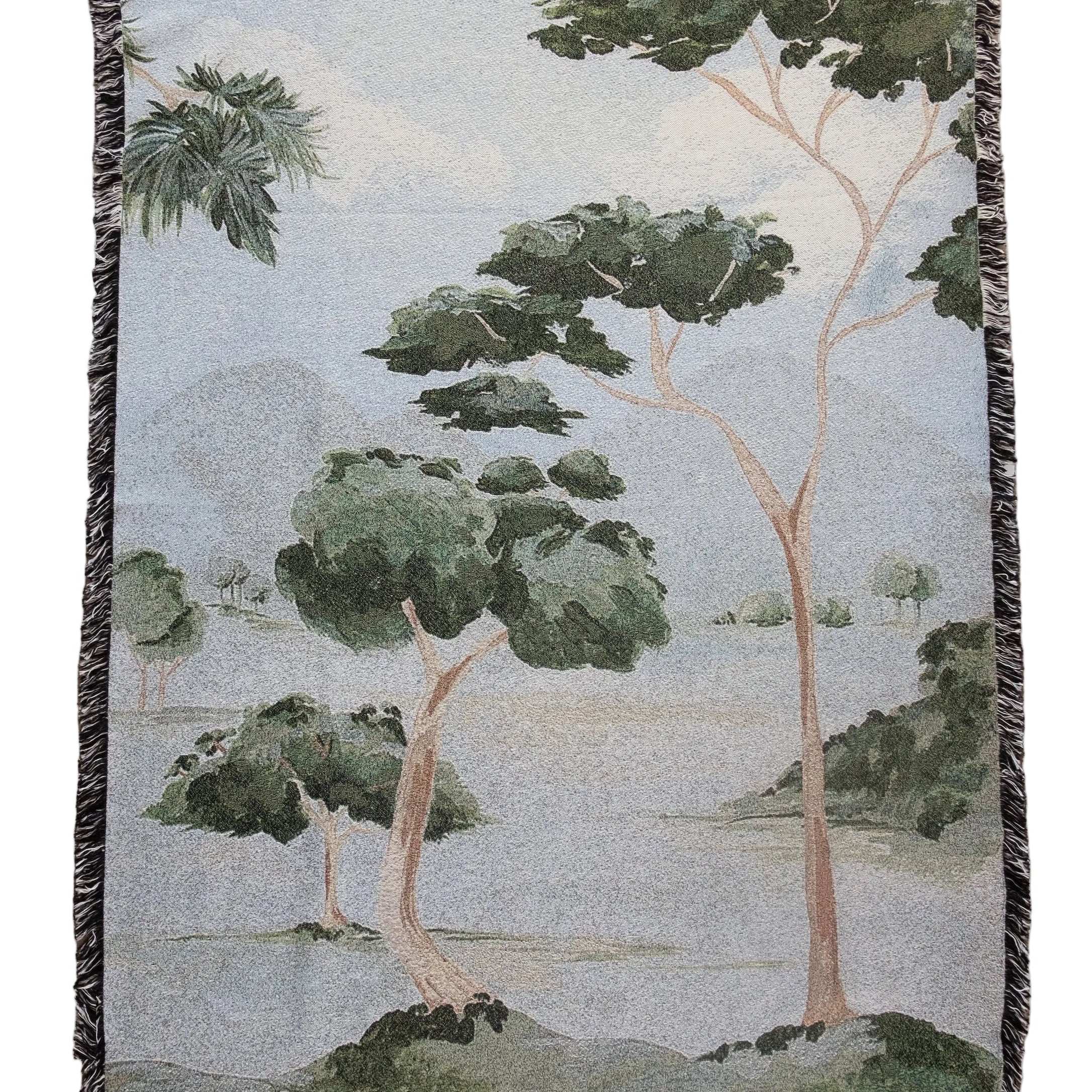 Woven blanket with a nature-themed design of trees and landscape on a plain background
