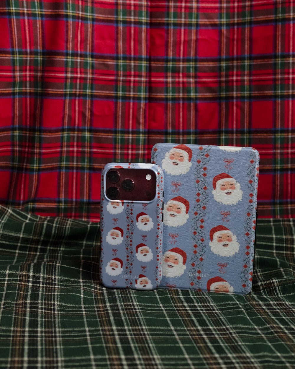 Jolly phone case and Santa Kindle case standing on green plaid
