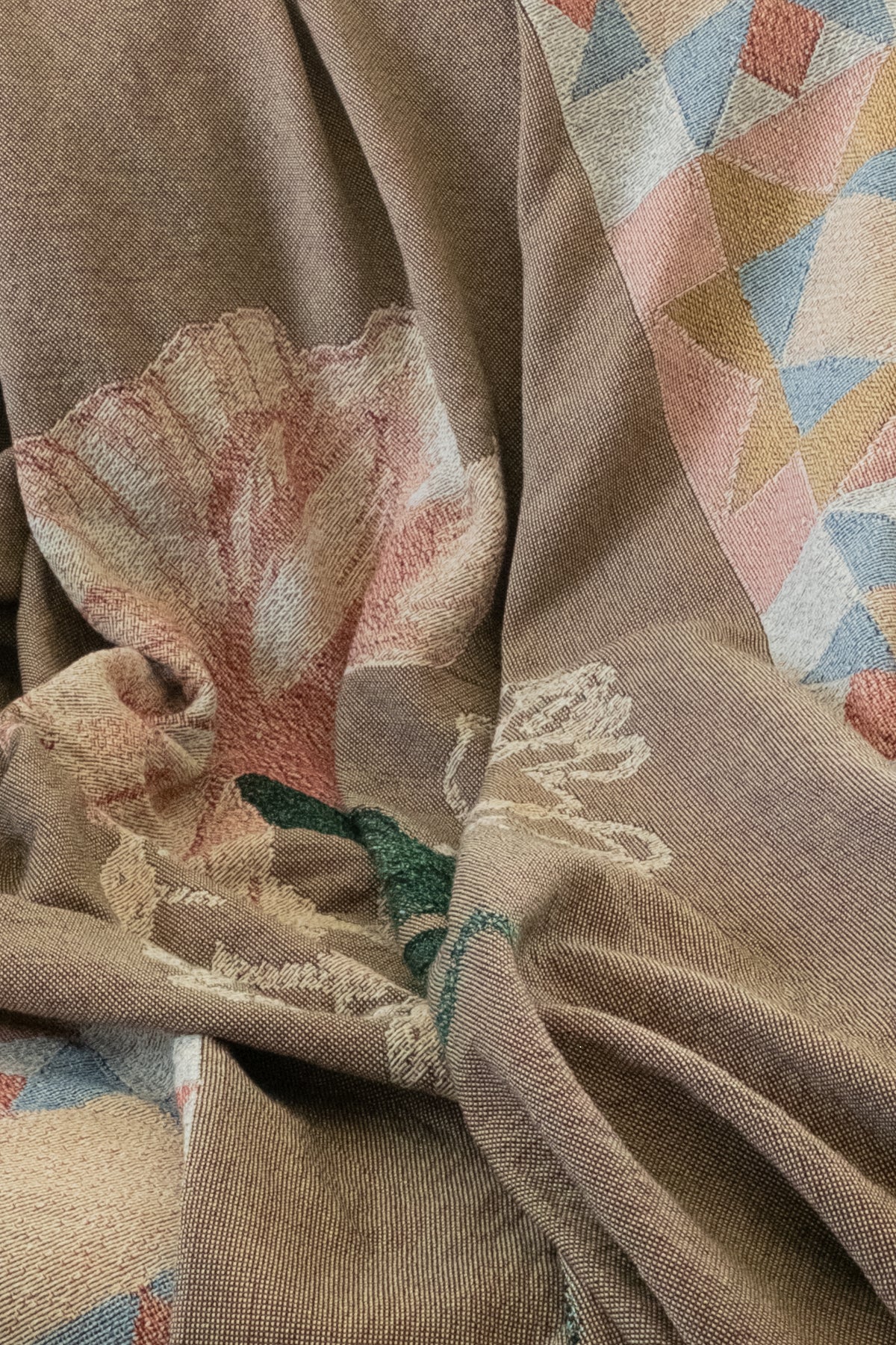 Draped brown woven fabric featuring a pink floral pattern and a geometric border of colorful triangles.