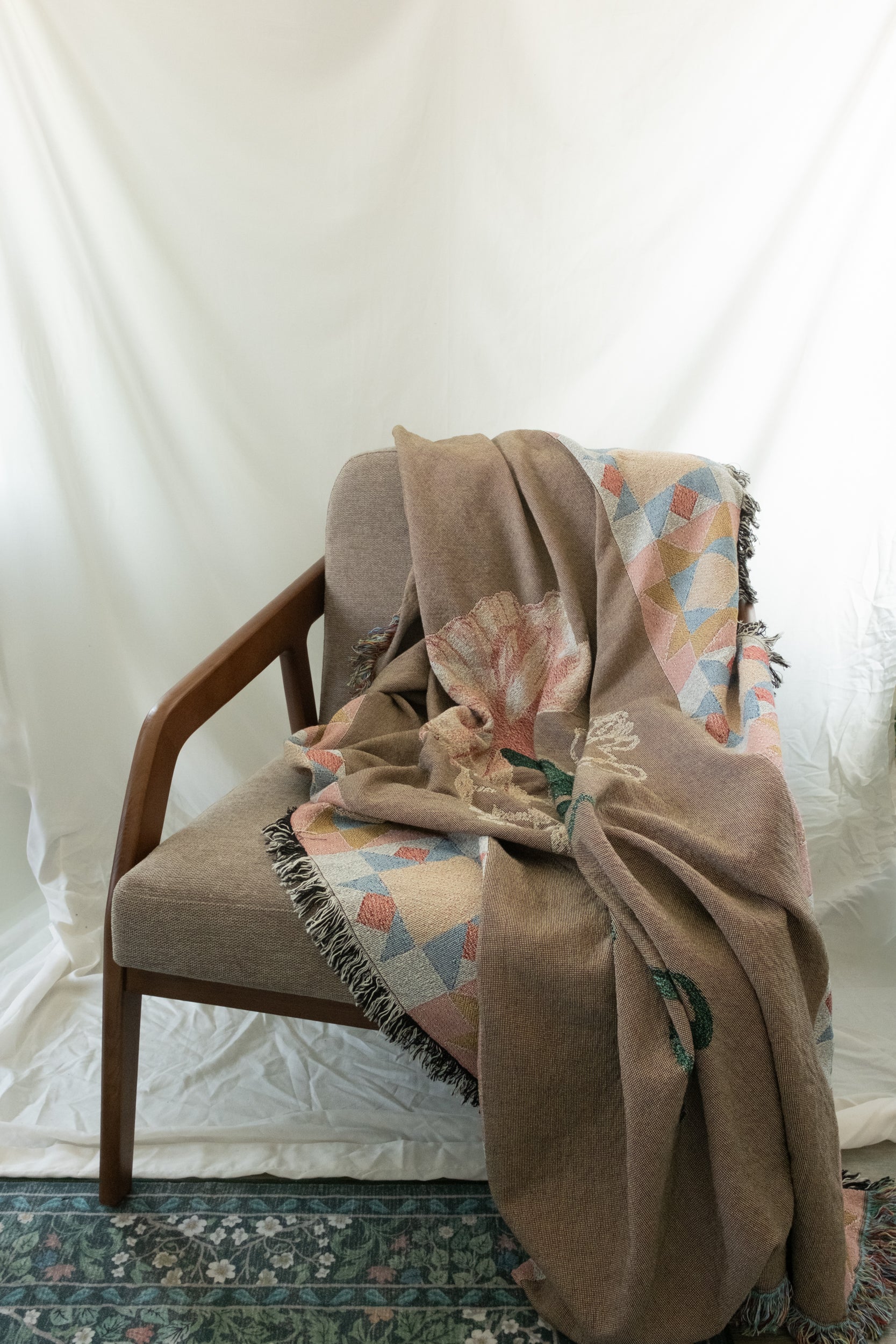 Brown woven January Birth Month blanket with floral and geometric patterns draped over a wooden armchair.