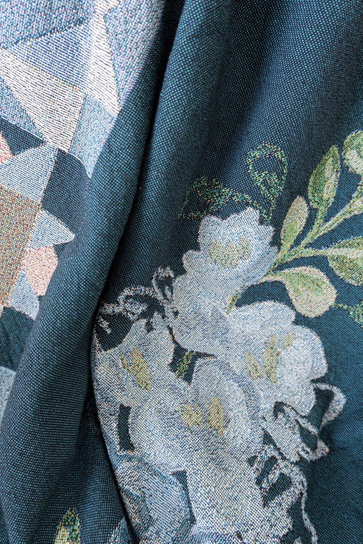 Draped dark teal woven fabric featuring a light blue and white floral pattern with green leaves.