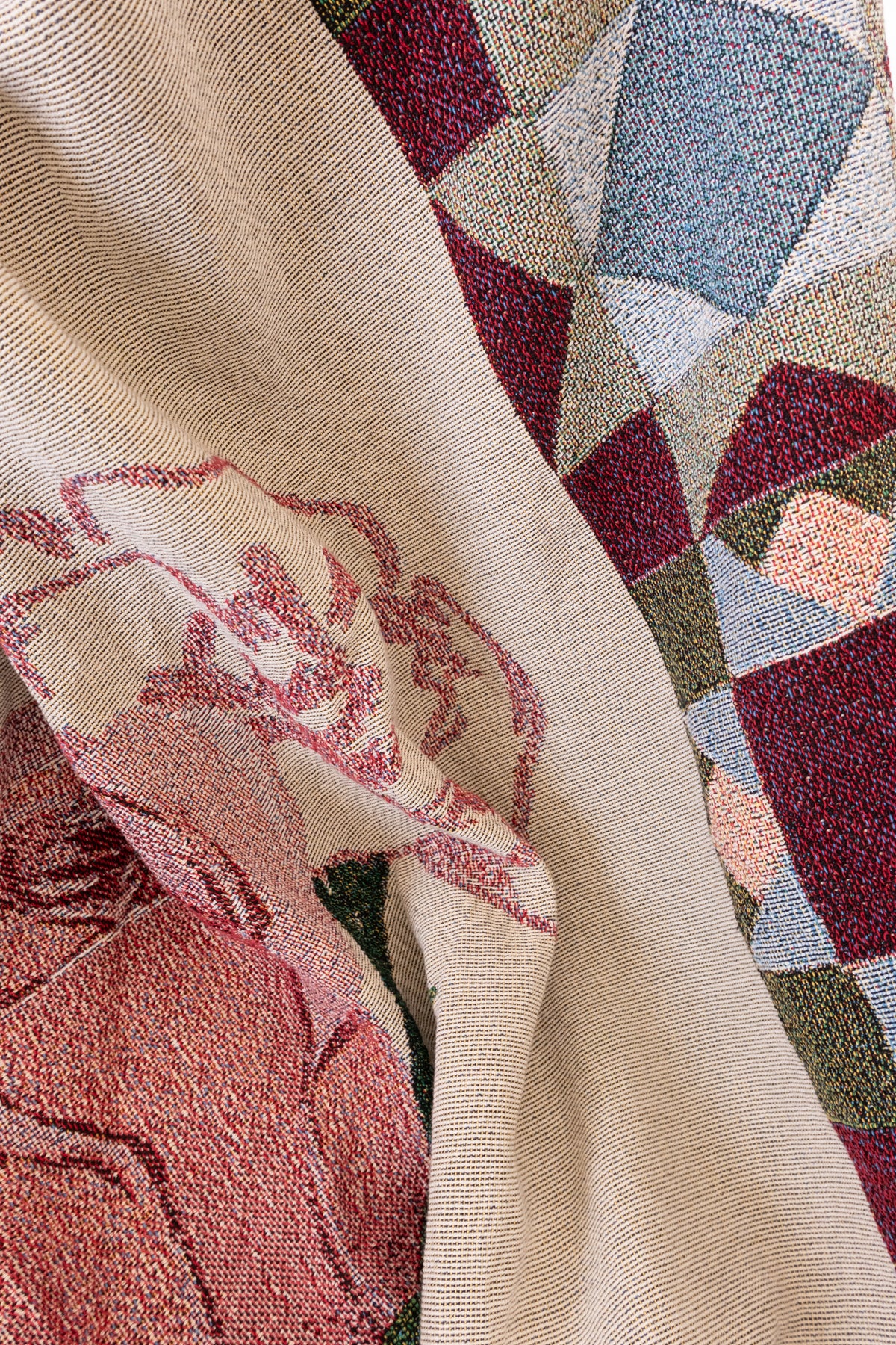 Draped cream woven fabric featuring a red floral pattern and a geometric design in blue, burgundy, and green.
