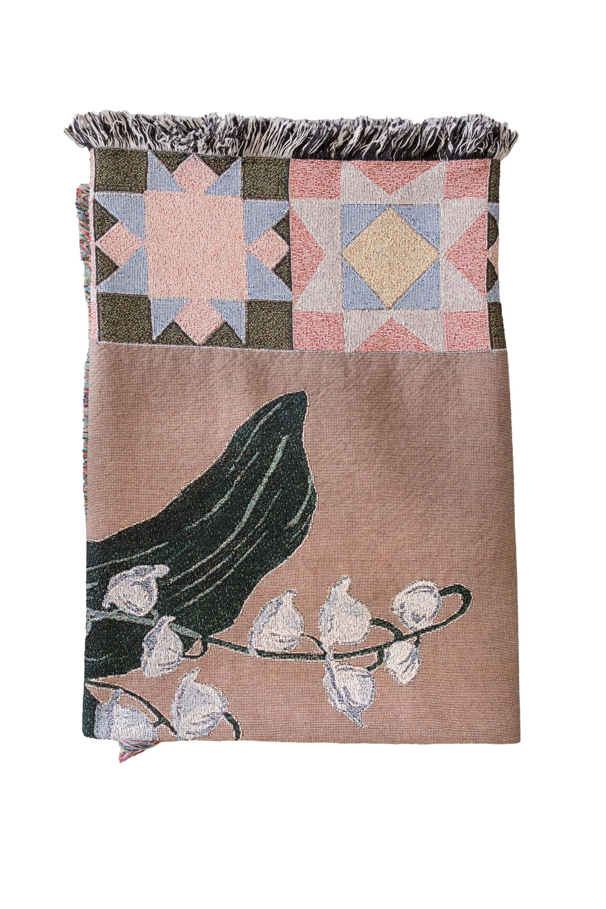 Folded tan woven fabric blanket with fringed edges, lily of the valley floral design, and geometric star patterns.