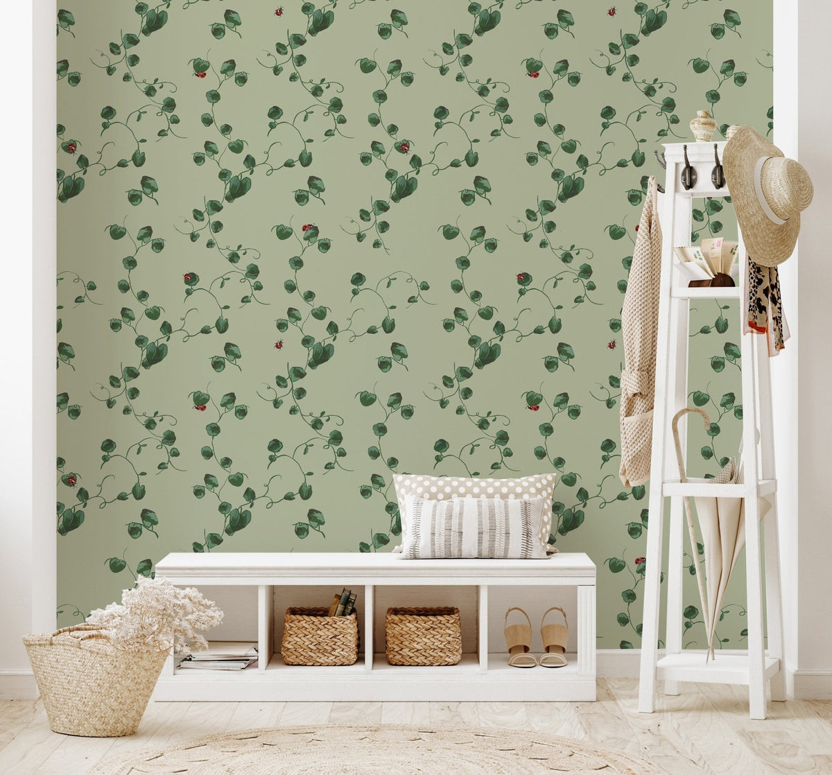 Green Albie wallpaper with a vine and ladybug pattern behind a white bench and coat rack in a mudroom.