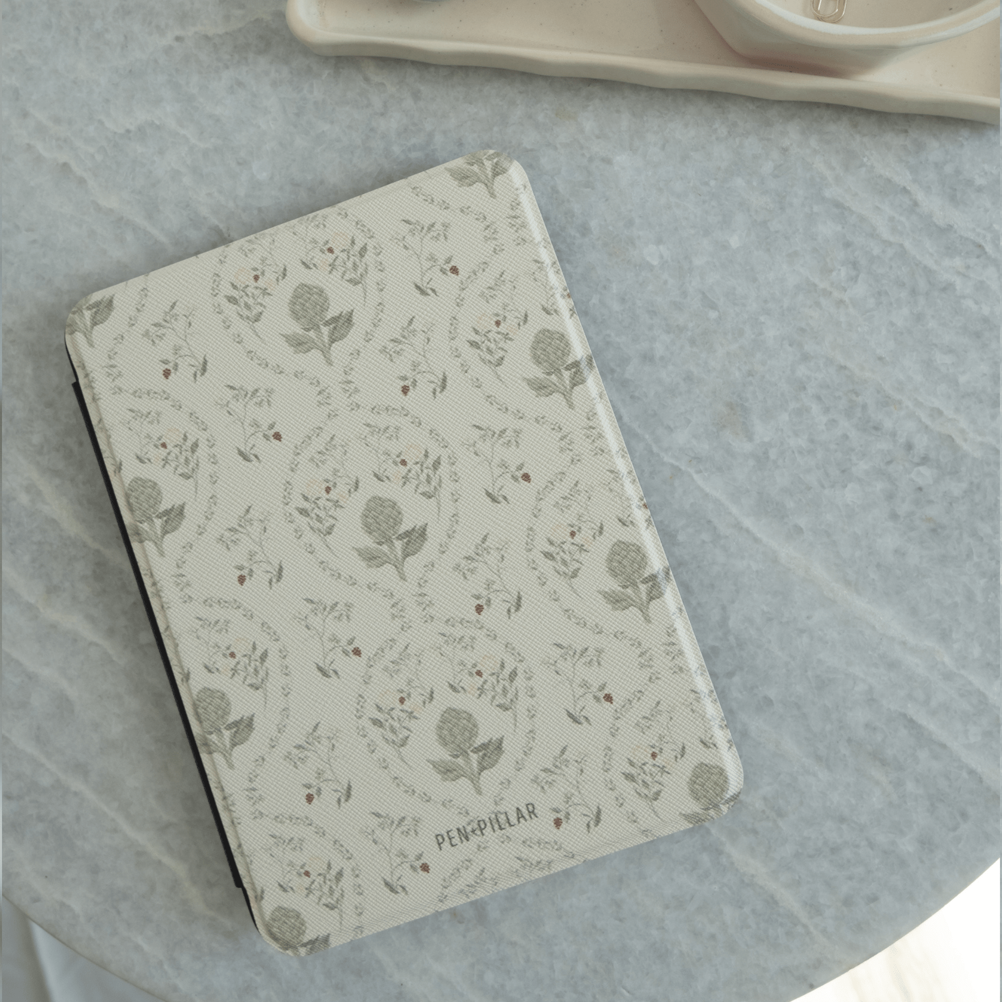 Artichoke Kindle case with floral design on a light background, placed on a marble surface.