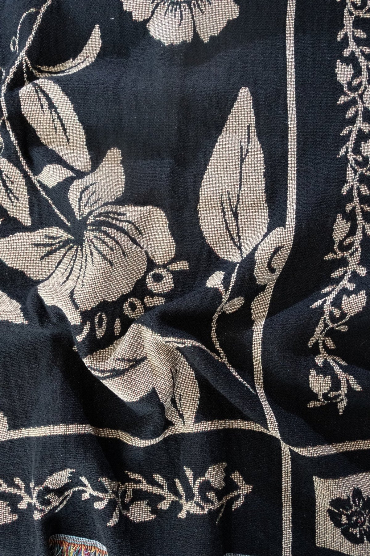 Bramble woven blanket featuring a floral design in cream on a dark navy background.