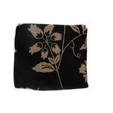 Bramble woven blanket featuring a black background with beige floral patterns.