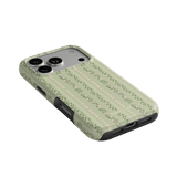 Camellia iPhone case featuring a floral pattern on a light green background, angled view showing camera cutout.