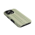 Camellia iPhone case featuring a green floral pattern with small pink flowers and leaves, angled view showing camera cutout.
