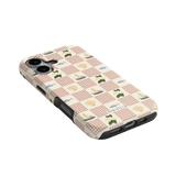 Coastal iPhone case featuring a checkered pattern with sailboats, trees, and seashells in soft colors.