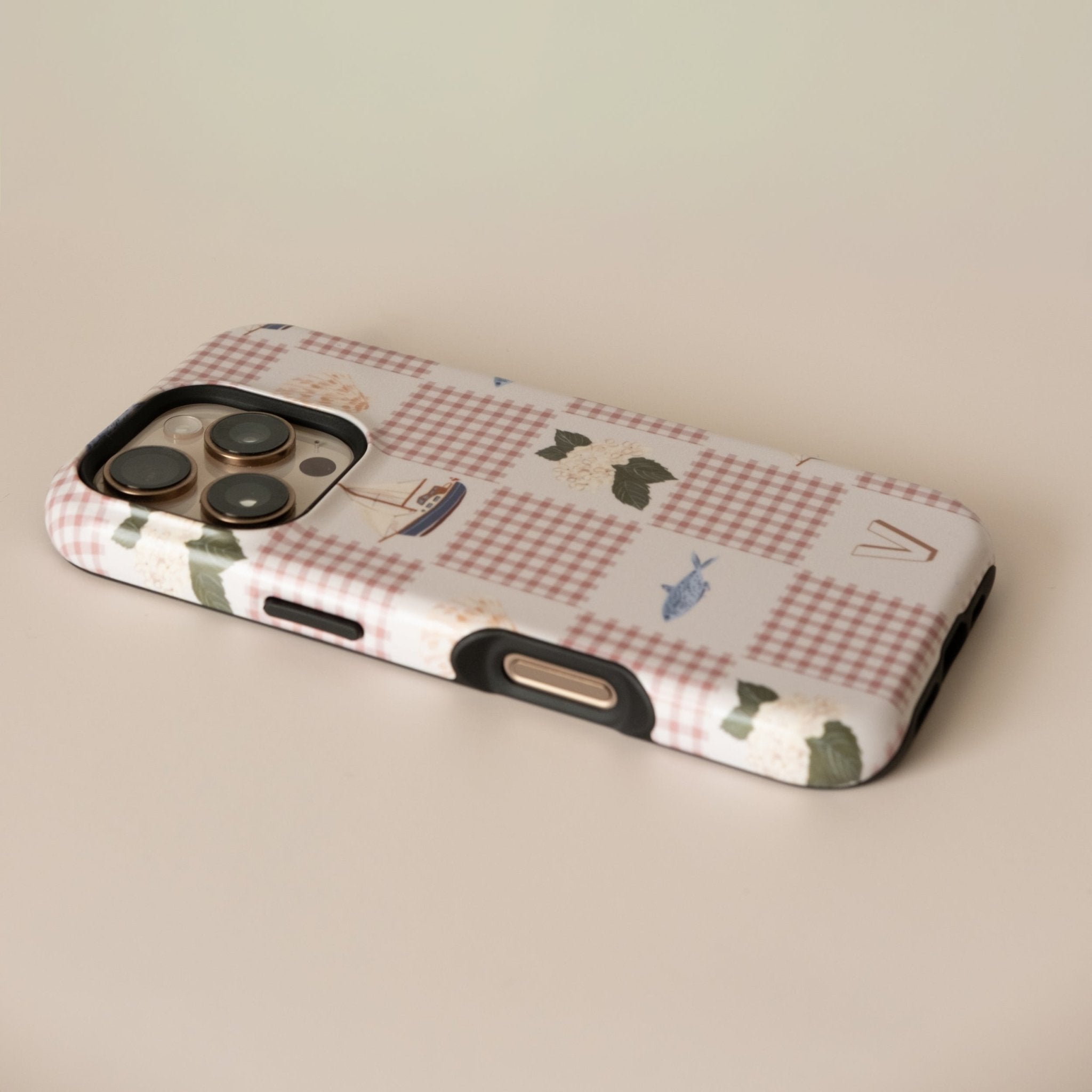 Coastal personalized iPhone case featuring a checkered pattern with boats and greenery, viewed from an angle.