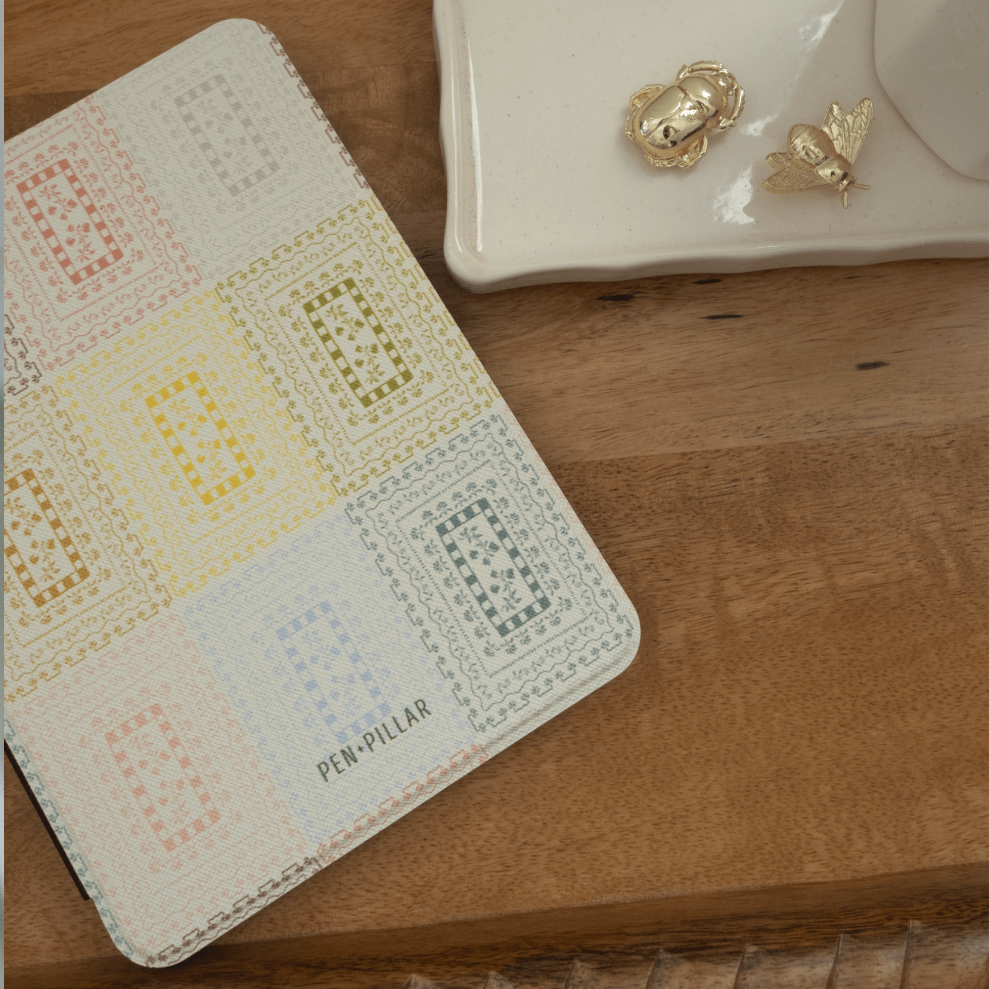 Curio Kindle case featuring a colorful geometric pattern on a wooden surface with decorative items nearby.
