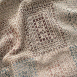 Curio woven blanket featuring intricate patterns in earthy tones of beige, red, and blue.