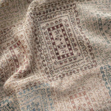 Curio woven blanket featuring intricate patterns in earthy tones of beige, red, and blue.