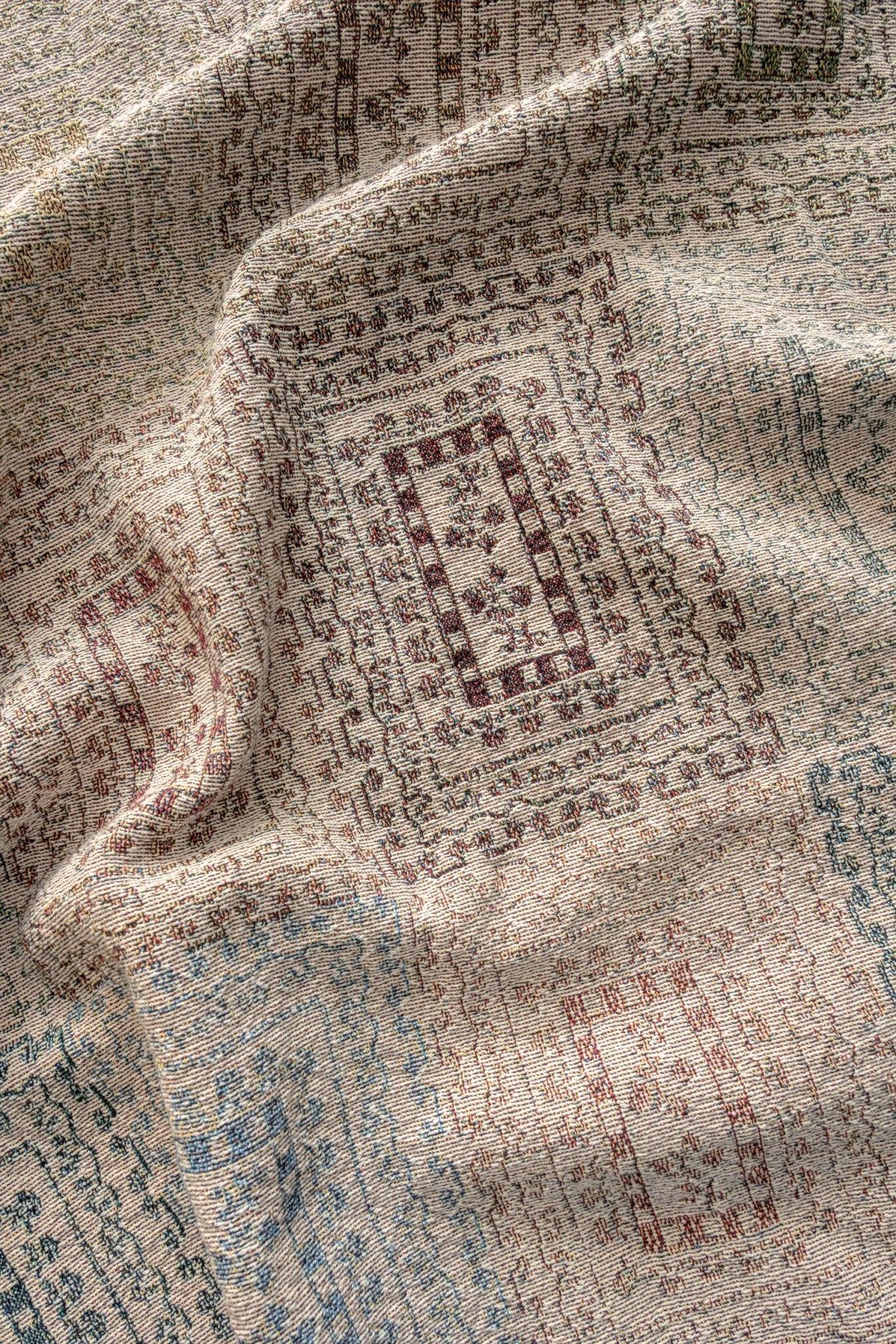 Curio woven blanket featuring intricate patterns in earthy tones of beige, red, and blue.