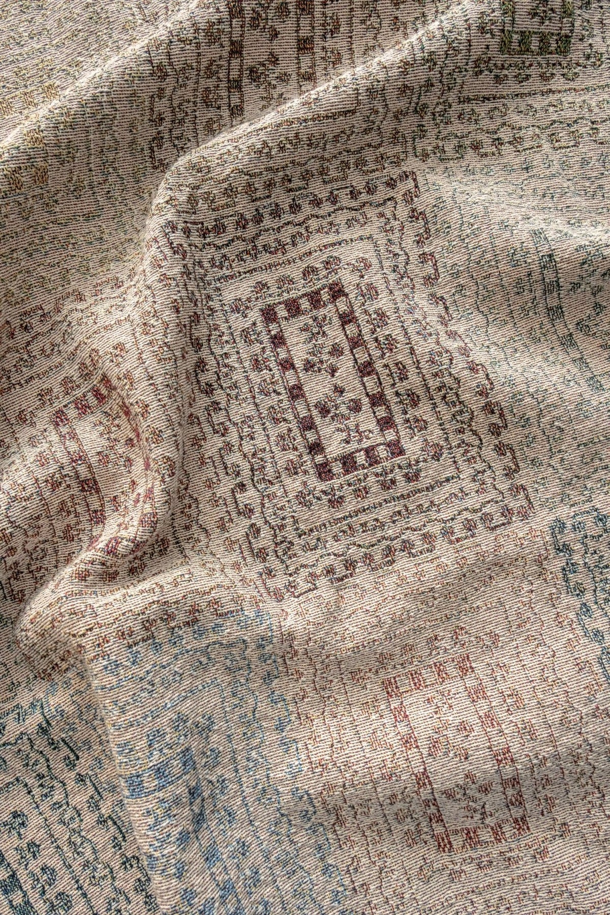 Curio woven blanket featuring intricate patterns in earthy tones of beige, red, and blue.