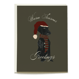 Festive Otis holiday card featuring a black dog wearing a red hat and striped scarf with "Warm Seasons Greetings" text.