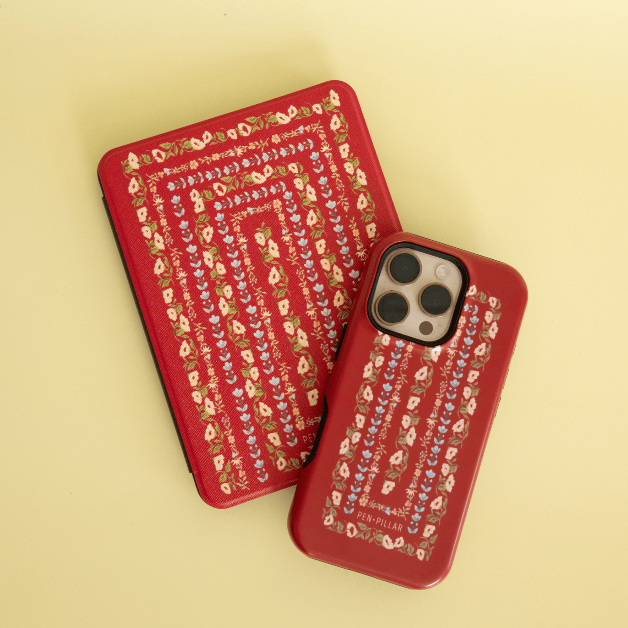Fiona Kindle case featuring a red floral pattern with a matching phone case, both on a light yellow background.