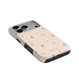 Forage iPhone case in light pink with floral patterns and black edges, showcasing camera cutouts and ports.