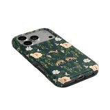 Forest iPhone case featuring floral and deer patterns on a dark green background, angled view showing buttons and ports.
