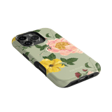 Garden Rose iPhone case featuring pink and yellow floral designs on a light green background, angled view.