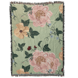 Garden rose woven blanket featuring large floral patterns in pink and yellow on a green background with fringe edges.