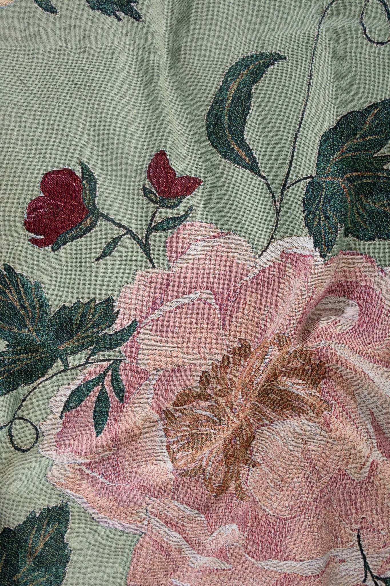 Garden rose woven blanket featuring large pink and red floral patterns on a green background.