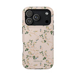 Grove iPhone case with a floral design featuring green leaves and light-colored flowers on a soft pink background.
