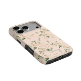 Grove iPhone case featuring a floral design in soft colors with a black trim, angled view showing camera cutout.