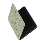 Grove Kindle case with a floral design in soft green, partially open to reveal the Kindle device inside.