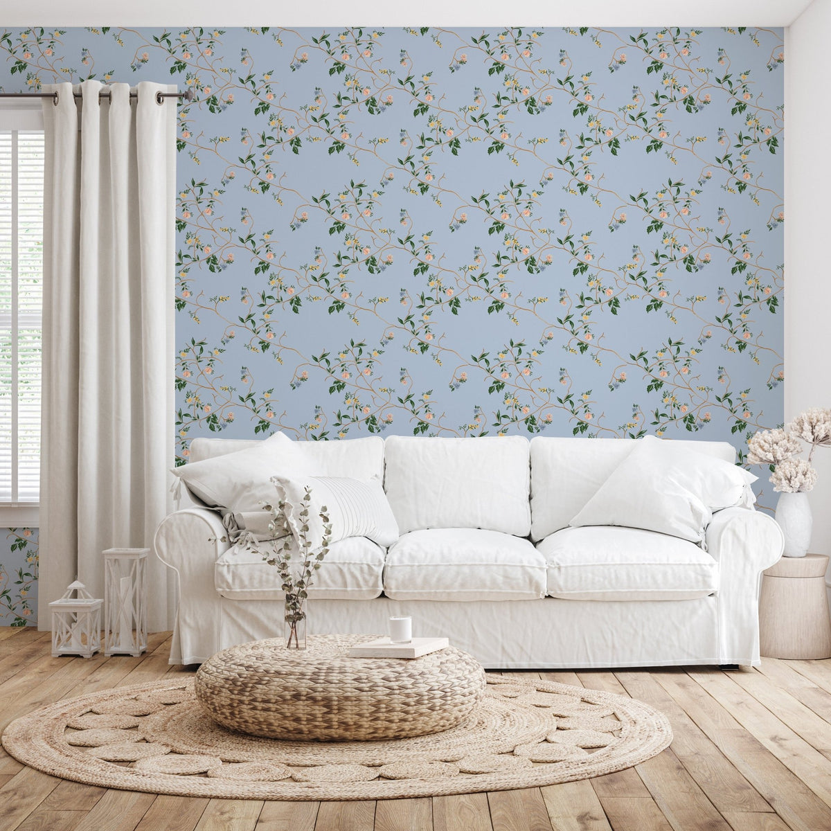 Blue Grove floral wallpaper with green leaves and pink flowers behind a white fabric sofa and woven round rug.