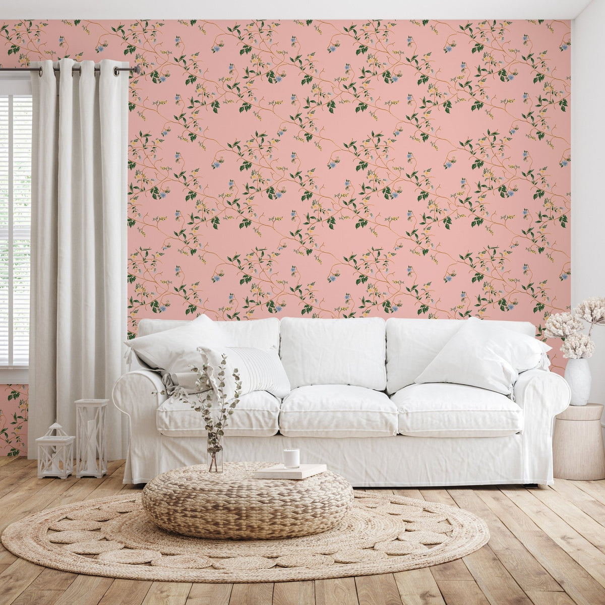 Pink floral wallpaper with green leaves behind a white fabric sofa, round woven rug, and wood floor.