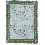Grove woven blanket featuring a light blue background with floral patterns and green borders, fringed edges.