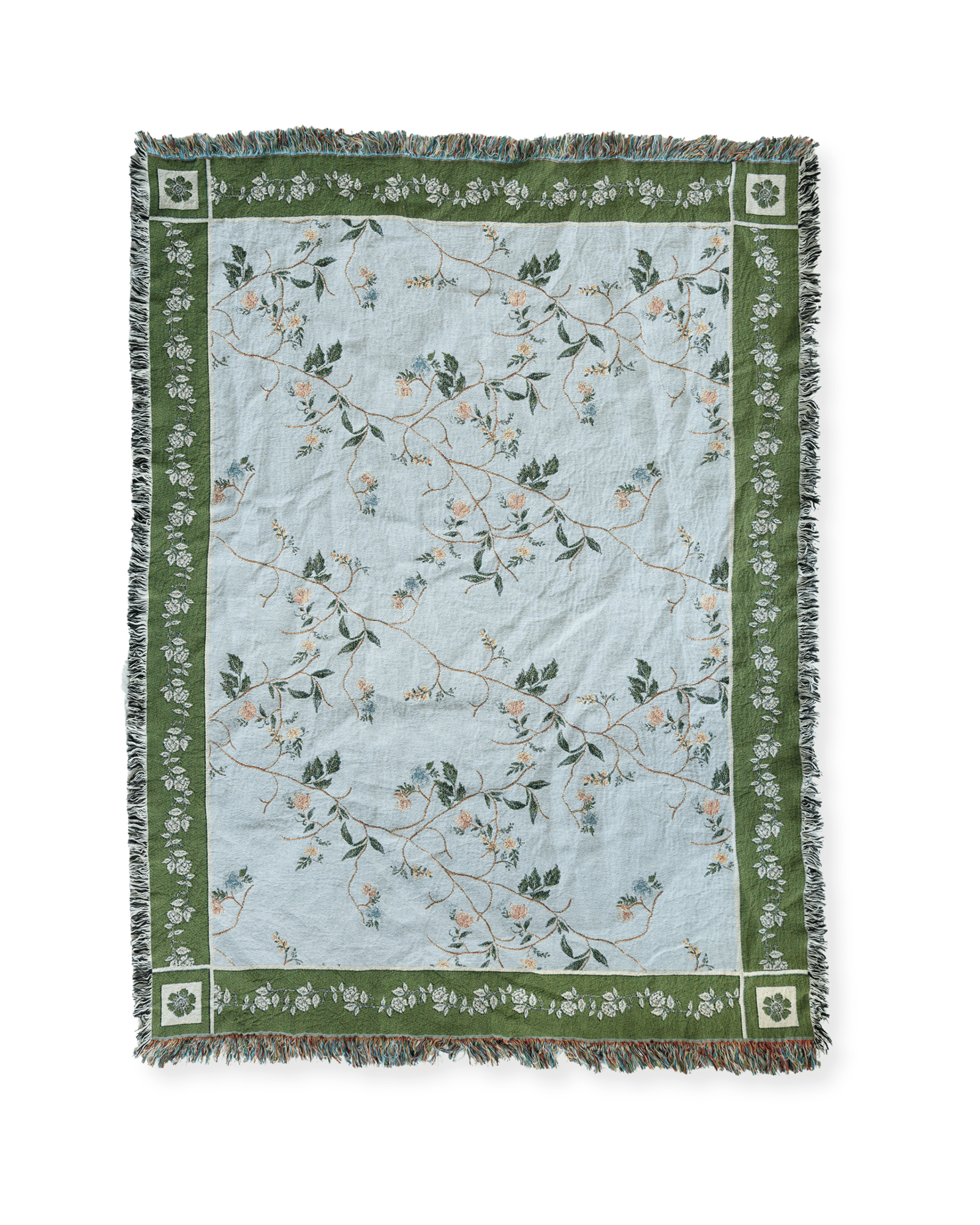 Grove woven blanket featuring a light blue background with floral patterns and green borders, fringed edges.