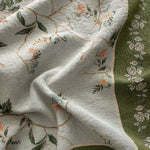Grove woven blanket featuring floral patterns in soft colors on a textured fabric with green and cream tones.