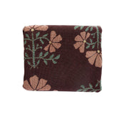 Haven woven blanket featuring a maroon background with floral patterns in pink and green.