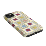 Heirloom iPhone case featuring a geometric pattern in pastel colors with a glossy finish, angled view showing ports.