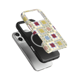 Heirloom iPhone case featuring a colorful geometric pattern, layered over a black and silver phone case.