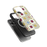 Heirloom iPhone case featuring a colorful geometric pattern, layered over a black phone case with a circular design.