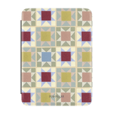 Heirloom Kindle case featuring a geometric patchwork design in muted colors, with a logo at the bottom.