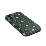 Meadow iPhone case featuring a floral pattern on a dark green background, angled view showing camera cutouts.